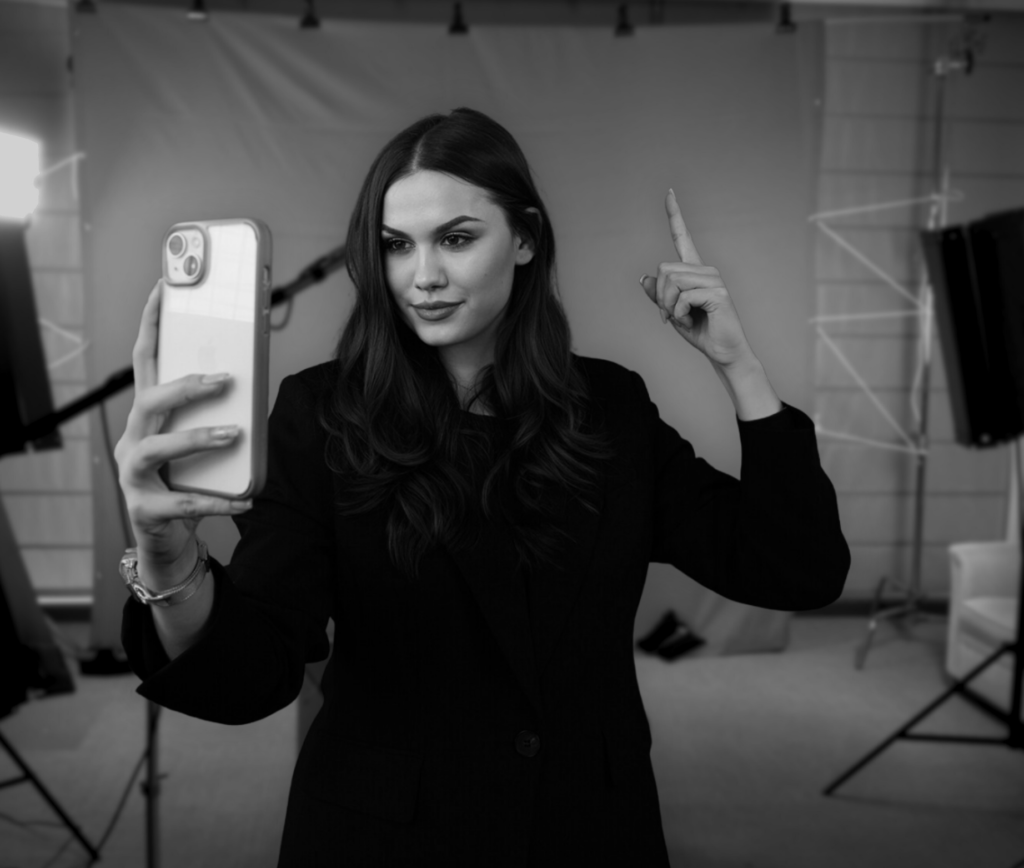 Eine Frau die ein Selfie in einem Studio macht und in den Himmel zeigt